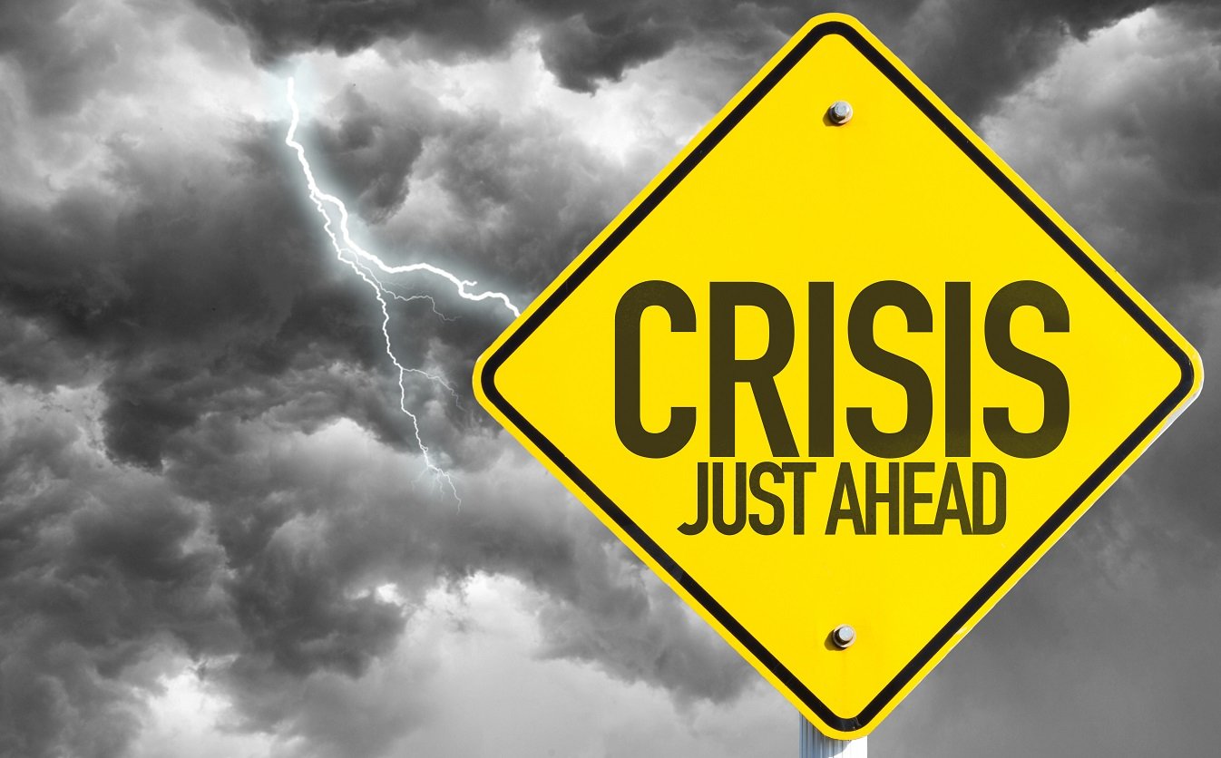 Yellow yield sign saying "Crisis Just Ahead"